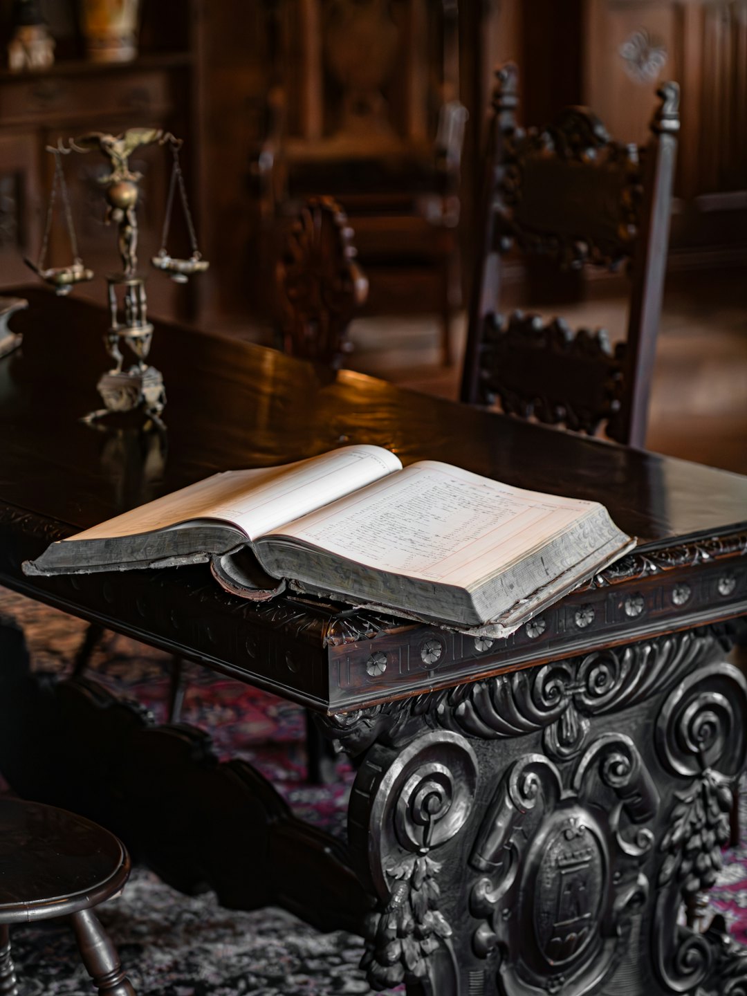 Open ledger book on a polished wooden table with a scale of justice.